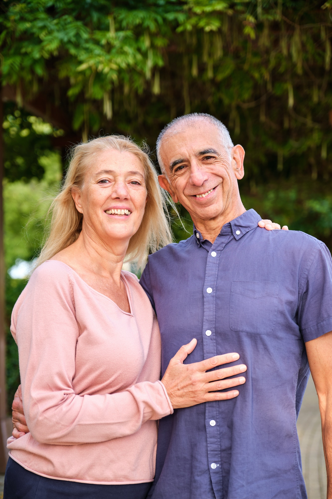 Happy mature couple looking at camera in a park at street.